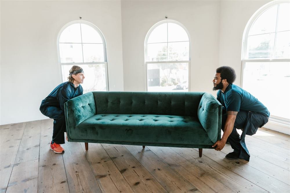 Two men carrying a sofa out during a house clear-out