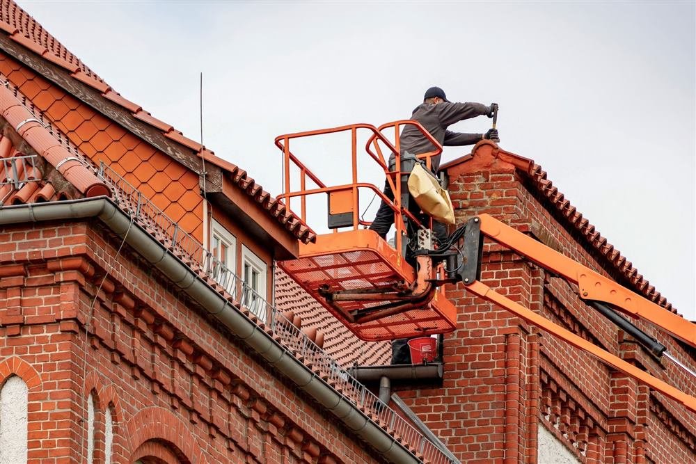 Roofer repairing the roof of a red brick building